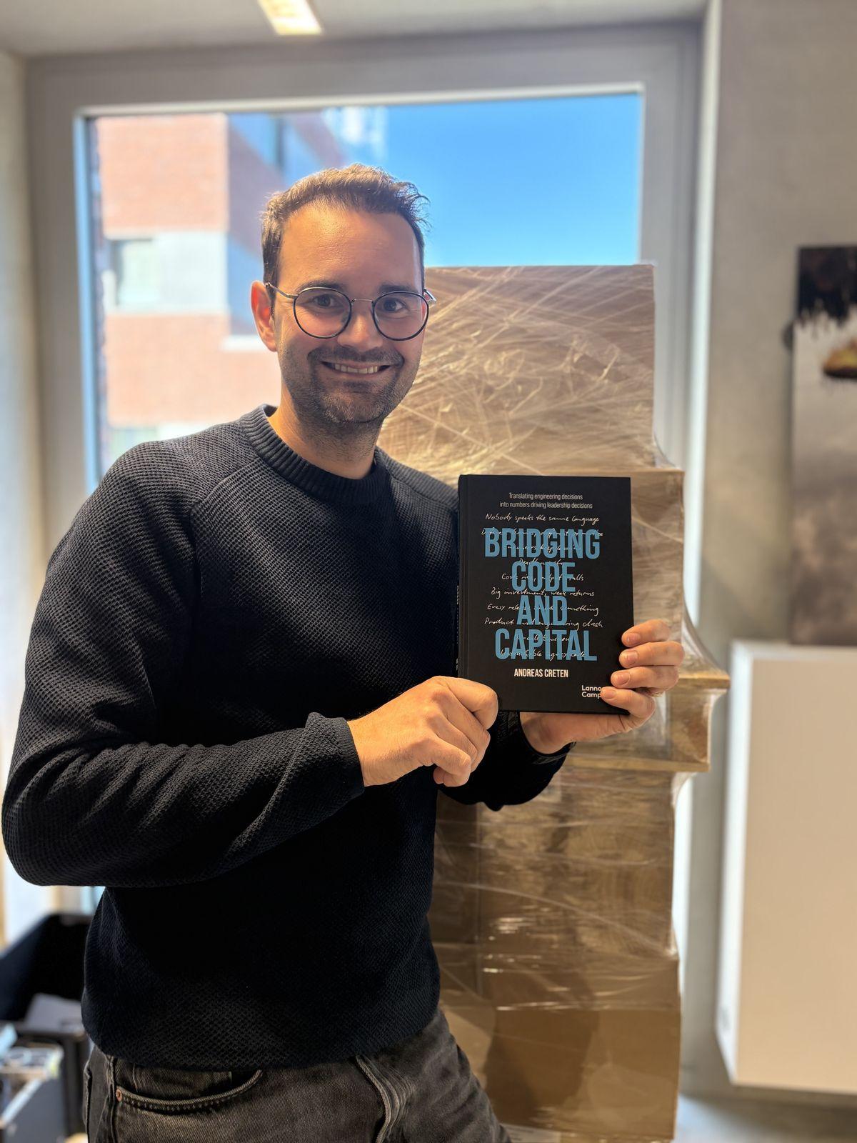 Andreas Creten holding Bridging Code and Capital in front of a pallet of freshly delivered copies