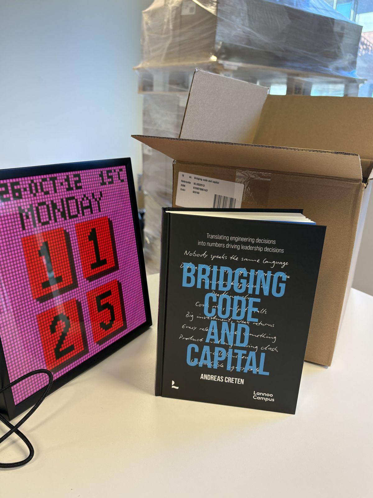 A copy of Bridging Code and Capital standing next to an opened box of copies in the madewithlove office