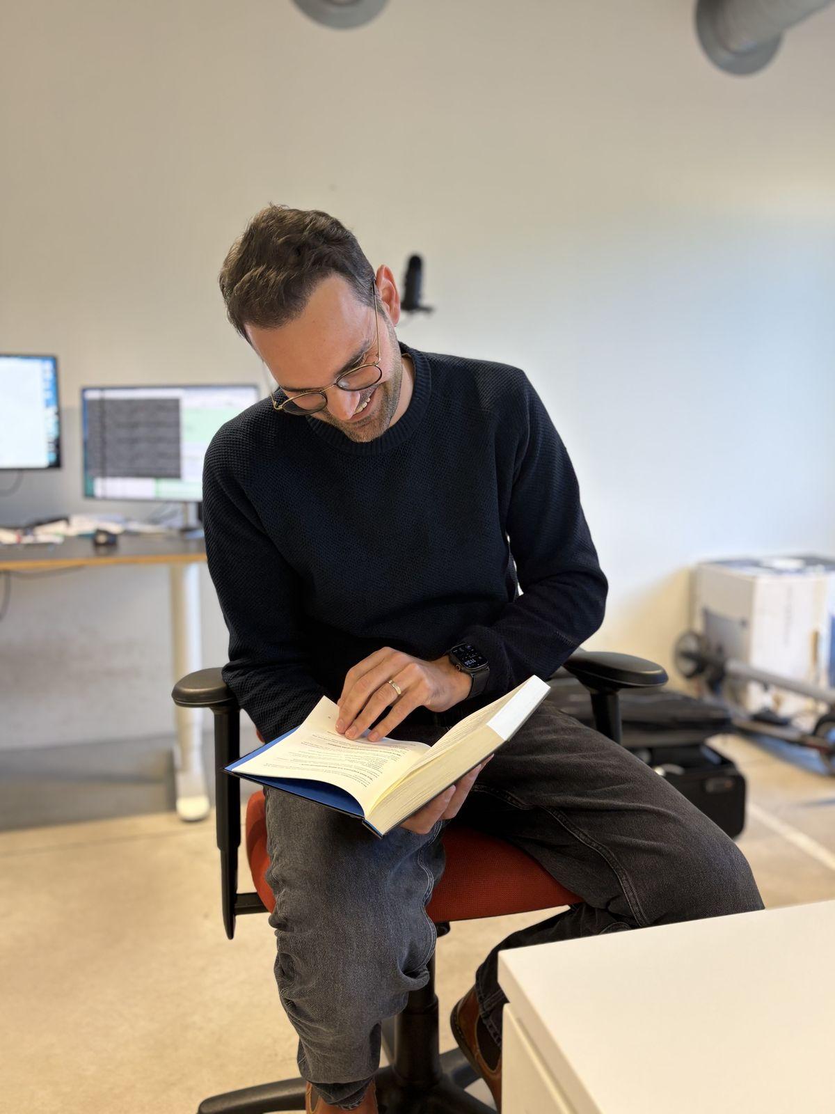 Andreas Creten leafing through a copy of Bridging Code and Capital at his desk